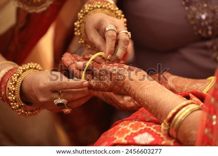 Indian wedding rituals. Indian bride getting her wedding bangles. Indian Mother helping putting bangles on bride hand Royalty-Free Stock Photo #2456603277