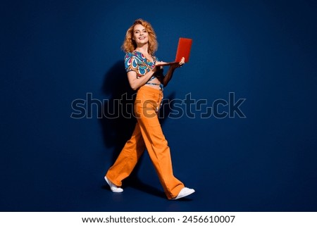 Full size photo of pretty young use laptop walk empty space woman wear top isolated on dark blue color background