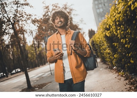 Photo of positive cheerful arabian man tourist enjoying vacation walking going outside urban city street