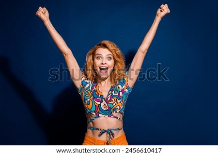 Photo of pretty young woman raise fists shout yes wear top isolated on dark blue color background
