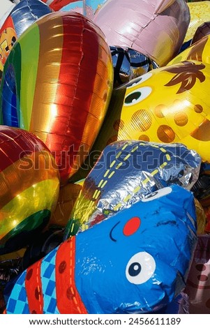 A bunch of multicolored air balloons filled with helium. Balloons of different shapes. Rainbow, blue sloth, yellow giraffe, pink pig. Photographed May Day Vappu- festival in Finland