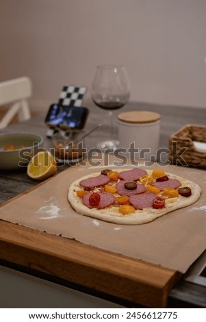 Pizza dough, movie evening, red wine, lemon, recipe, homemade pizza, cheese, sauce, salami, cherry tomatos Royalty-Free Stock Photo #2456612775