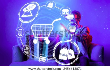 Happy man using VR headset and shopping online while sitting at sofa with shopping bags. Smart person looking at online market hologram and icon with neon background. Innovation technology. Deviation.