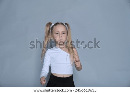 Focused child in dance attire, with her hair tied in playful pigtails, capturing a moment of determination and poise. Royalty-Free Stock Photo #2456619635