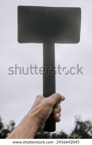 A strong man, a Scandinavian superhero, holds a heavy hammer in his hands at work. Photography, mythology concept, victory signal.