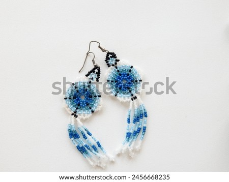 Subject shot of beaded earrings made as flowers. Decorative blue floral earrings