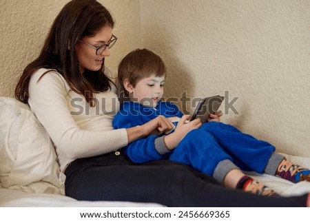 Mother, child and tablet in home bedroom for learning, education and storytelling with boy online. Mom, kid and digital tech on bed for game, relax or family streaming cartoon on internet together