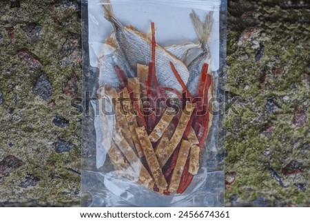 food set of small cut sea dry fish and dried squid in a transparent bag on a gray table
