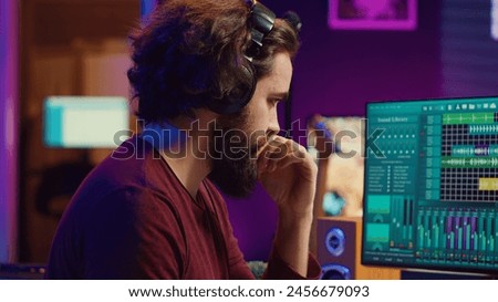 Music producer engages in post production with editing and time aligning recorded songs. Musician using digital audio workstations to manipulate tunes, adding audio effects. Camera A.
