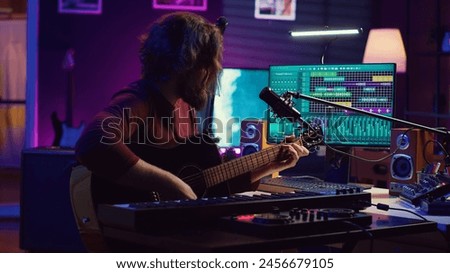 Creative songwriter singing a song on microphone and playing his guitar, acoustical engineering technology with daw software on pc. Artist creating music with instrument and mixing console. Camera A.