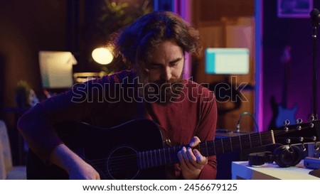 Young man playing guitar and creating music using equalizer daw software interface. Music producer recording song in home studio and mixing acoustic sounds on stereo console. Camera A.