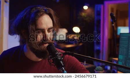 Artist singing a song at microphone and playing electronic piano to create music in home studio. Songwriter recording midi controller sounds, adjusting volume with pore amp knobs. Camera B.
