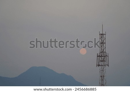 picture of moon in the morning beetween silhouette of mountain and antenna