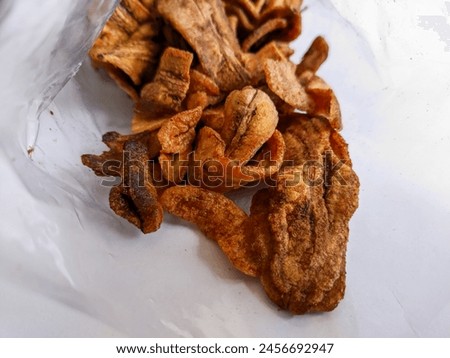 Delicious and sweet banana chips in a plastic bag on a white background