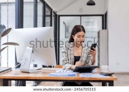 Portrait of young Asian businesswoman in suit, woman smiling and work at workplace inside office, accountant with calculator behind paper phone signing contracts and financial reports	
