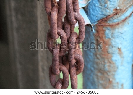 Small rusty chain, to lock the fence. Full of brown rust due to weather and lack of maintenance.