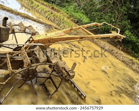 photo of a tractor parked in the middle of a rice field, because it has been used. Royalty-Free Stock Photo #2456757929
