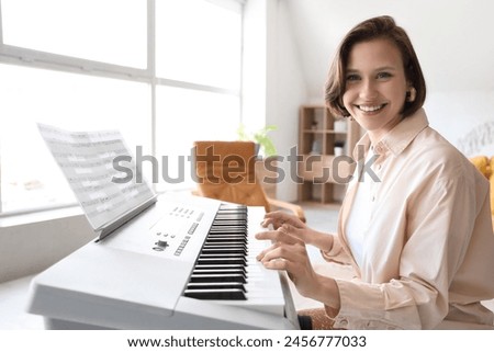 Young woman playing synthesizer at home Royalty-Free Stock Photo #2456777033
