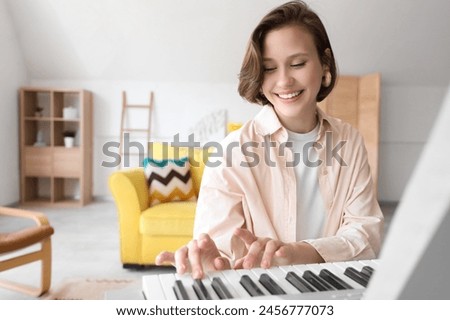 Young woman playing synthesizer at home Royalty-Free Stock Photo #2456777073