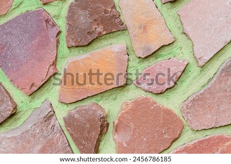 It is the photo of the colorful stones on green background. Its close up of multicolored stone wall of building. It is photo of mosaic tile floor. It's view of wall texture.