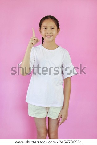 Portrait of Smiling Asian young girl pointing up index finger or forefinger on pink isolated studio background.