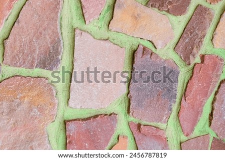 It is photo of colorful stones on the green background. Its close up of multicolored stone wall of building. It is photo of mosaic tile floor. It's view of wall texture.