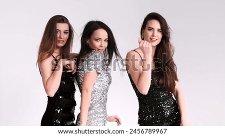 Bright young women of different nationalities dance and rejoice, on an isolated background. A professional shot of three best friends having fun and posing. Lifestyle, style and fashion concept.