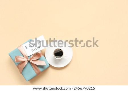 Cup of coffee, gift box and paper with text I LOVE YOU, DAD on beige background. Father's day celebration. Top view