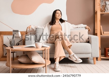 Young woman resting on grey sofa at home Royalty-Free Stock Photo #2456790779