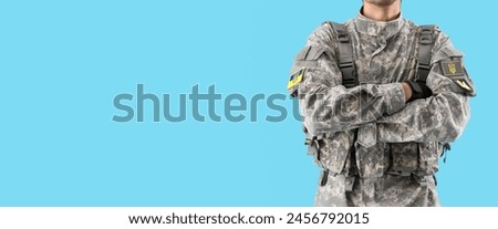 Young male Ukrainian soldier on light blue background with space for text