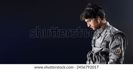 Young male Ukrainian soldier on dark background with space for text