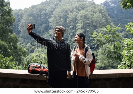 Young couple taking self-portrait while hiking through the forest