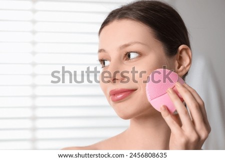 Washing face. Young woman with cleansing brush indoors, closeup. Space for text