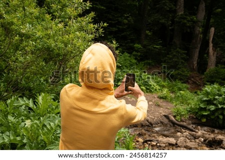A young attractive guy takes a photo on his phone. Beautiful nature.