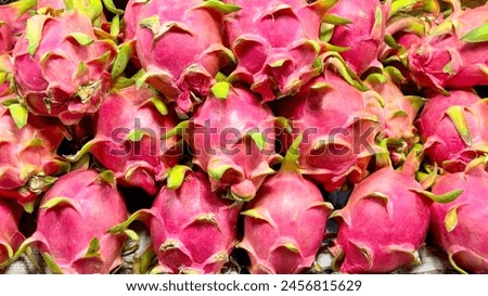 Fruit backdrop with vibrant pink dragon fruit stacked at a market, highlighting the fruit's role in wellness trends due to its antioxidant properties and appeal in visually driven food markets