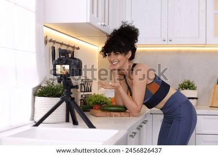 Smiling food blogger explaining something while recording video in kitchen Royalty-Free Stock Photo #2456826437