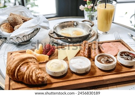A wooden tray topped with a generous assortment of delectable food items, including fruits, cheeses, meats, and pastries, ready to indulge your taste buds. Royalty-Free Stock Photo #2456830189