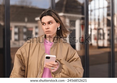 Single sad girl waiting for a phone call walking outside. Blonde woman with short hair look unhappy, waiting for answer from her boyfriend. Royalty-Free Stock Photo #2456852621