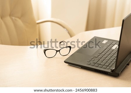 Glasses and laptop on the table. Royalty-Free Stock Photo #2456900883