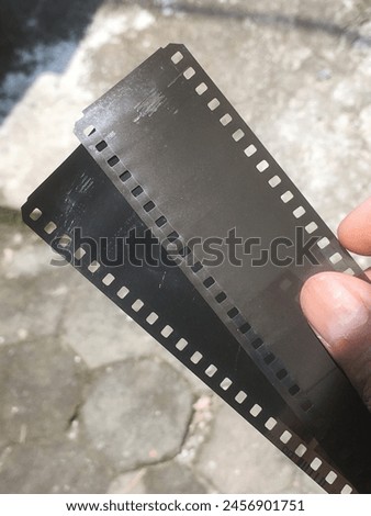 2 selulloid film strip colored black and dark brown hold by right hand