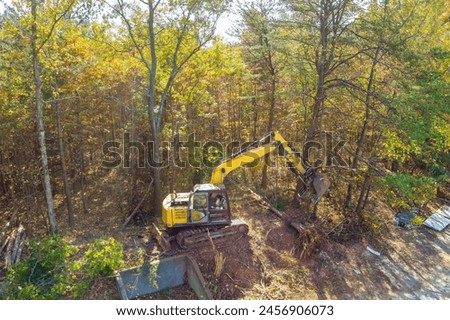 Preparation of land for construction, use of an excavator tractor to uproot trees make space for construction of house Royalty-Free Stock Photo #2456906073