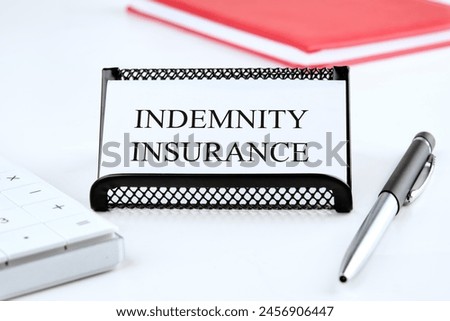 Business concept. INDEMNITY INSURANCE text written on a business card on a white background