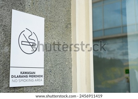 'No Smoking in this area' sign on a building exterior stucco brick wall