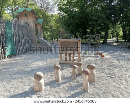 Wooden drawing board and chairs like mushrooms. Sandpit, modern ecological safety children outdoor playground equipment in park. Nature, green trees, design concept background kids area 