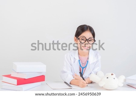 Cute little girl asian with stethoscope playing doctor, wear medical uniform and glasses, holding stethoscope playing doctor,