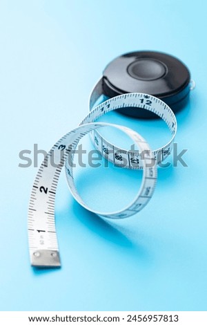 Tape measure on a blue background. Royalty-Free Stock Photo #2456957813