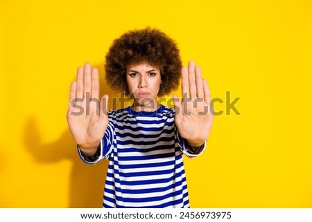 Portrait of pretty young woman arms show stop empty space wear striped shirt isolated on yellow color background
