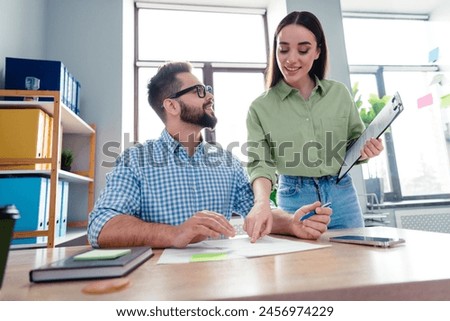 Photo of happy cheerful employers dressed shirts discussing paper work indoors workshop workstation