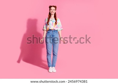 Full length photo of adorable lovely positive woman wear print shirt jeans trousers stand like doll isolated on pink color background