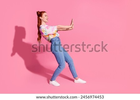 Full size photo of positive girl dressed colorful blouse jeans hold palms say stop look empty space isolated on pink color background